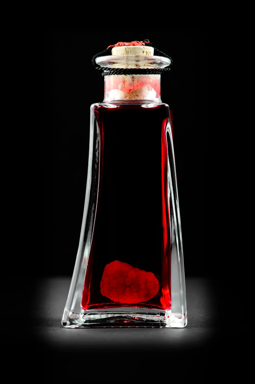 Une framboise entière dans une bouteille de liqueur de framboises