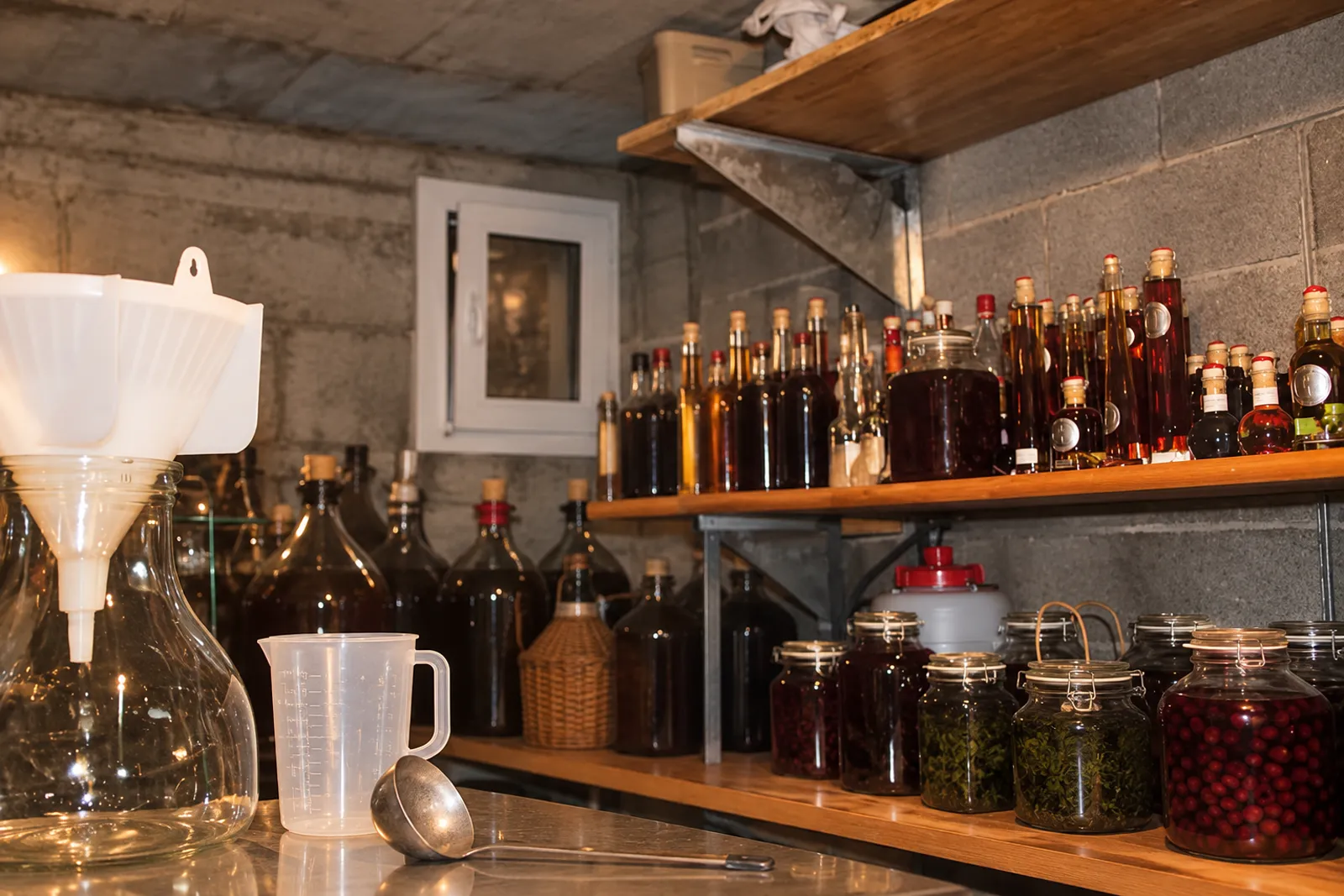 L'atelier de Stéphane : étagère de liqueurs, bocaux de fruits en macération, entonnoir